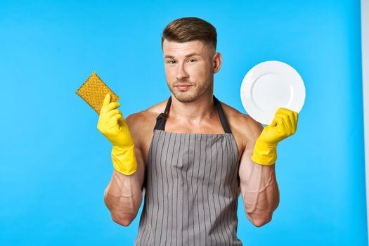 man in apron cleaning dishwashing blue background. High quality photo