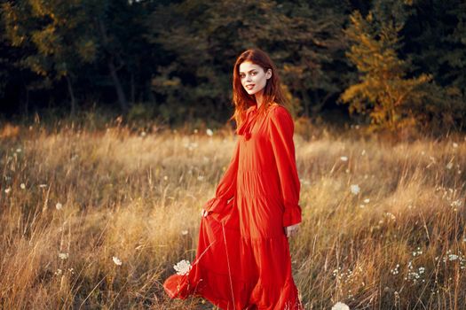 woman in a red dress in a field in nature summer landscape freedom. High quality photo