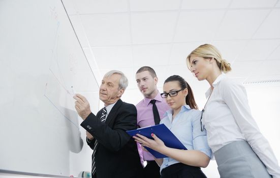 Senior male business man giving a presentation at a  meeting at modern light office on a table board