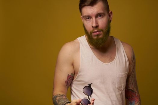 a bearded man with a serious expression in a white t-shirt with tattoos on his arms. High quality photo