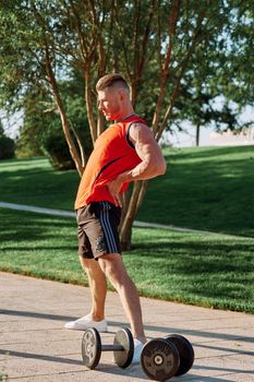 sporty man in the morning in the park with dumbbells exercise. High quality photo