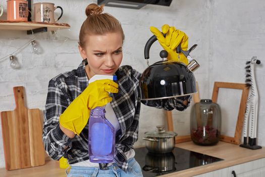 Domestic service and housekeeping concept, happy blonde lady cleaning kitchen kettle, close-up of hands in rubber gloves holding spray