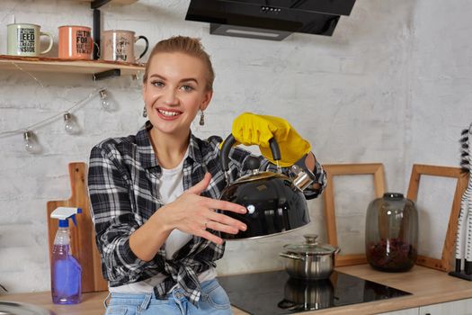 Domestic service and housekeeping concept, happy blonde lady cleaning kitchen kettle, close-up of hands in rubber gloves holding spray