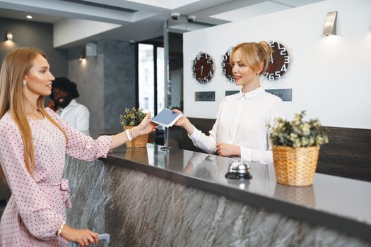 Young attractive woman with packed suitcase standing in hotel lobby close up