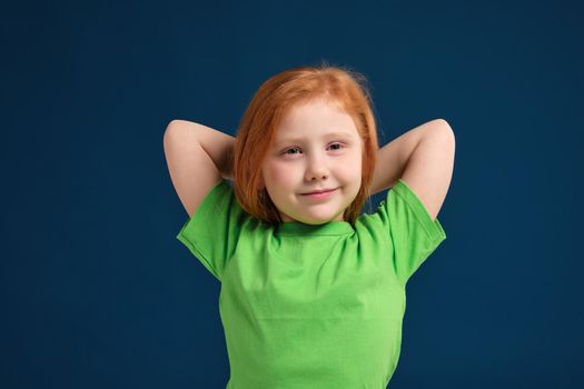 close up photo of little redhead emotional girl in green t-shirt posing before camera.She is tired and wants to sleep, yawning and stretching
