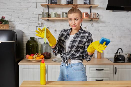 Household, cleaning and people concept - happy woman or housewife in rubber gloves wiping table with microfiber cloth at home kitchen.