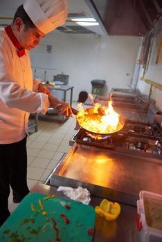 chef in hotel kitchen prepare vegetable  food with fire