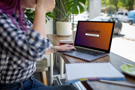 Side view of a young pink hair woman sitting in cafe, hand typing laptop computer with password login on screen. Cyber security concept