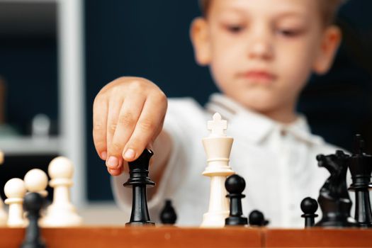 Close up photo of a little boy playing chess, makes a move