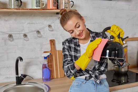 Domestic service and housekeeping concept, happy blonde lady cleaning kitchen kettle, close-up of hands in rubber gloves holding spray