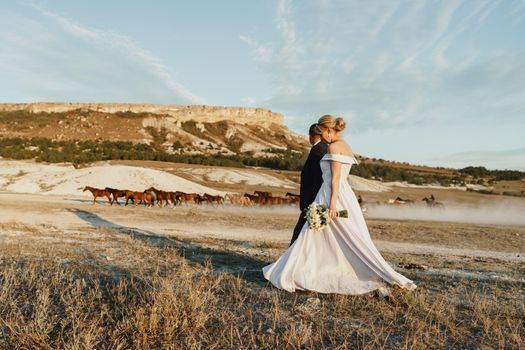 Bride and groom standing against big white rock in a field
