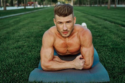 sporty man with muscular body pumping in park workout. High quality photo