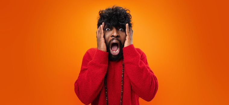 Young thrilled casual black man screaming on yellow background, close up