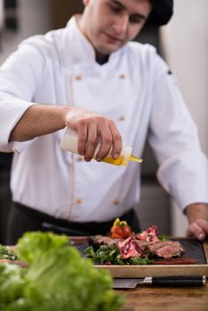 Chef finishing steak meat plate with Finally dish dressing and almost ready to serve at the table