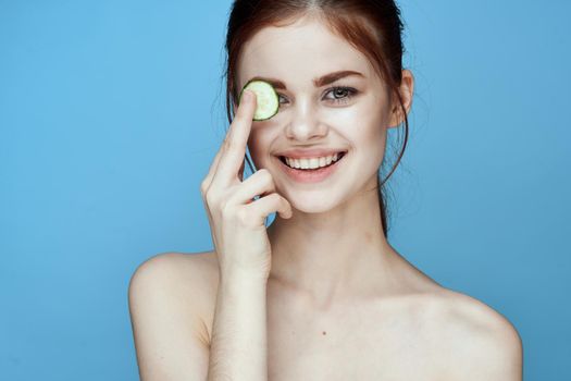 woman with bare shoulders cucumber vitamins health blue background. High quality photo