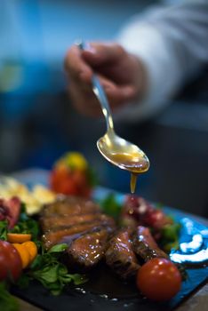 Chef hand finishing steak meat plate with Finally dish dressing and almost ready to serve at the table