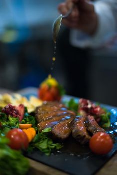 Chef hand finishing steak meat plate with Finally dish dressing and almost ready to serve at the table