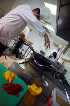 chef in hotel kitchen prepare vegetable  food with fire