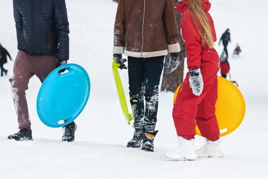 children with sleds in their hands are walking in the snow, winter vacation
