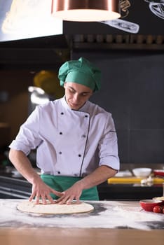 chef preparing dough for pizza rolling with hands on sprinkled with flour table