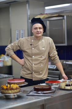 Closeup of a concentrated male pastry chef decorating dessert cake food in the kitchen