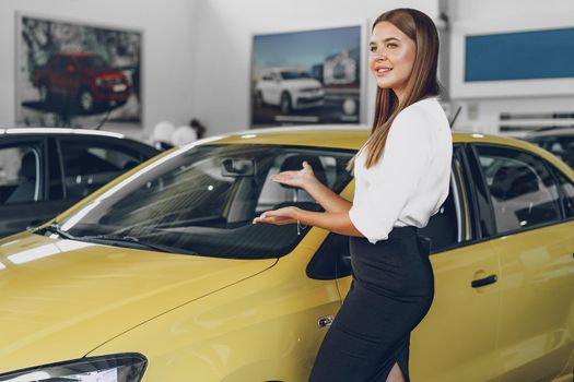 Young woman checking out a new car she is going to buy in car salon