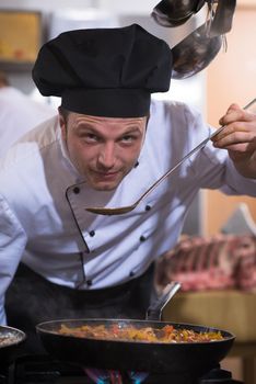 Handsome chef tasting food with spoon at the  restaurant kitchen