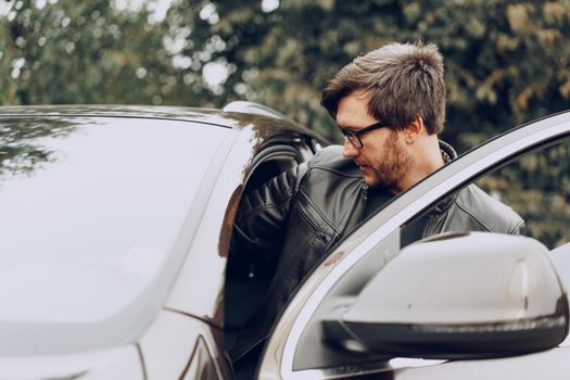 Stylish man in glasses sits in a car, close up portrait