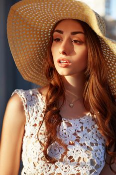 Close up portrait of a beautiful young woman near shop window during a sunny day. Lifestyle outdoors. Sunny lifestyle fashion portrait of young stylish woman walking on the street, wearing trendy outfit, straw hat, travel with backpack.