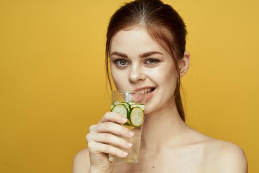 woman with cucumber drink vitamins body care yellow background. High quality photo