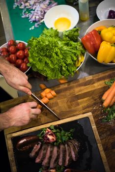 top view of Chef hands in hotel or restaurant kitchen serving beef steak with vegetable decoration