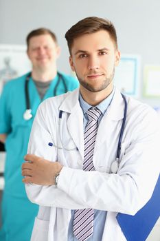 Two male medical workers in uniform at the workplace, close-up, vertical photo. Cooperation, team, clinic staff