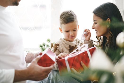 Smiling parents giving Christmas present to son at home, portrait