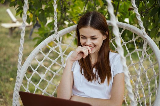 cheerful woman outdoors in hammock with laptop rest. High quality photo