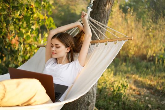 women outdoors lies in a hammock with a laptop freelance internet. High quality photo