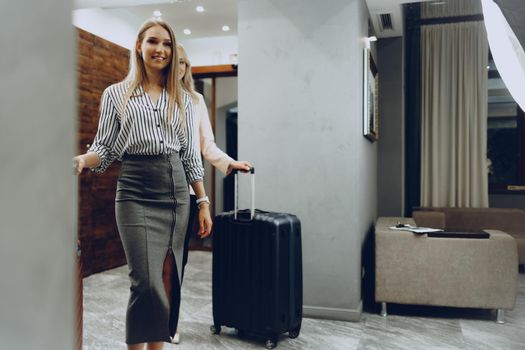 Two young women in formal clothes entering hotel lobby. Business trip concept