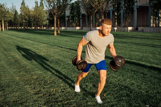 athletic man in the park workout exercise dumbbells. High quality photo