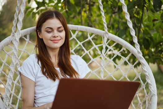 smiling woman outdoors in hammock with laptop technology. High quality photo