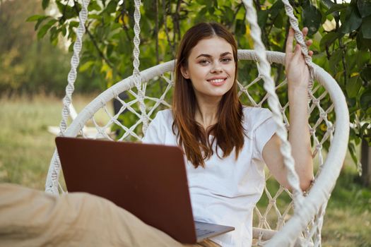 cheerful woman outdoors in hammock with laptop rest. High quality photo