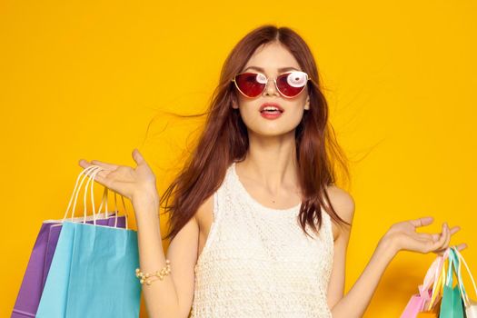 pretty woman wearing sunglasses posing shopping fashion yellow background. High quality photo
