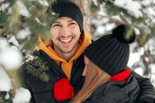 Close up photo of young couple in warm clothes standing together in a winter park