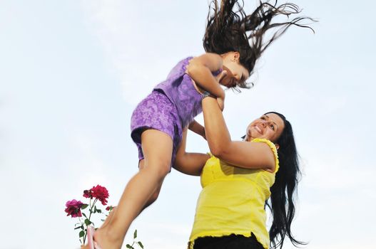 beautiful mom and daughter outdoor in garden  together with flower have fun and hug 