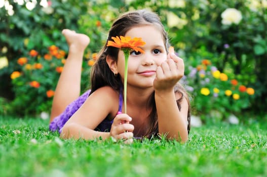 happy young girl children relax lie and have fun on grass with flower