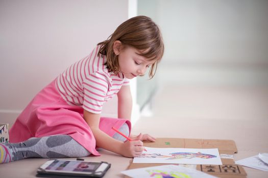 child playign at home while drawing colorful art and looking digital tablet