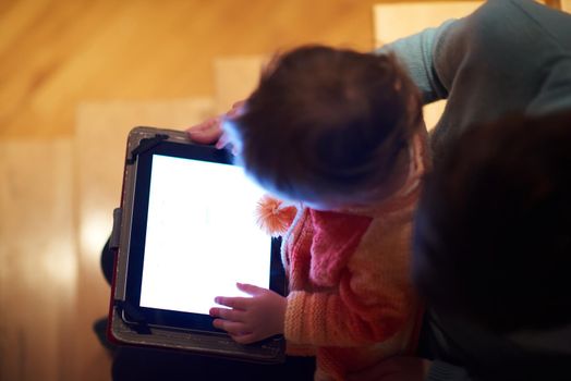 mom and child using tablet computer for internet surfing and photos at home top view