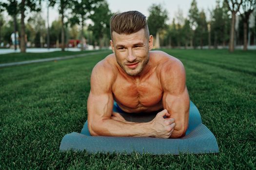 sporty man with muscular body pumping in park workout. High quality photo