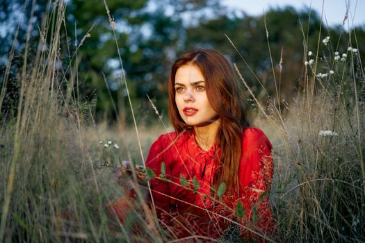 woman in a red dress lies on the grass in the field nature fashion. High quality photo