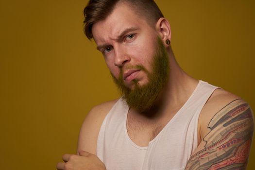 bearded man in white t-shirt with tattoos on his arms posing serious look. High quality photo