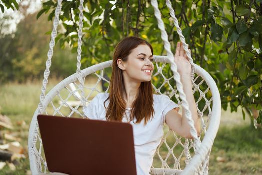 smiling woman outdoors in hammock with laptop technology. High quality photo