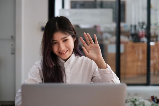 Cheerful young asian woman using laptop computer at home. Student female in living room. online learning, studying , online shopping, freelance, asean concept.